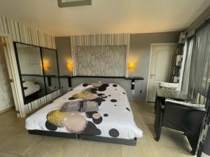 B&B Le Bouchat-Oreille في Spontin: غرفة نوم مع سرير مطبوع بقرة ومكتب