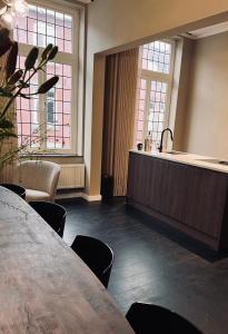Zimmer mit einem Tisch, einem Waschbecken und 2 Fenstern in der Unterkunft Het huis van Hermens in Meerssen