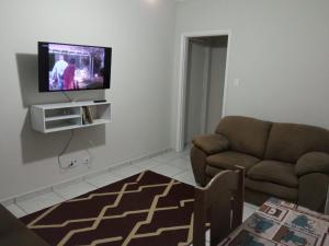 a living room with a couch and a flat screen tv at Espaço Acolhedor perto da Praia. in São Vicente