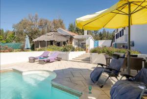 a patio with chairs and an umbrella and a pool at Villa Azul, Graça Portugal in Pedrógão Grande