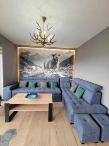 a living room with a blue couch and a painting of a sheep at Vidokówka Resort in Waksmund