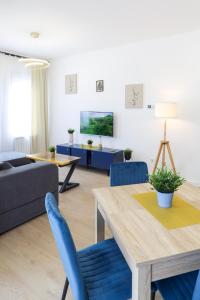 uma sala de estar com uma mesa e cadeiras azuis em Airport Belgrade Apartments em Surčin