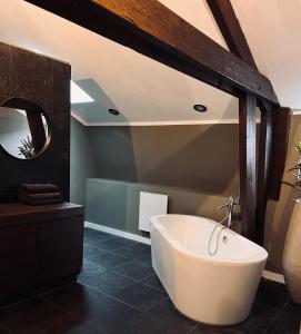 een badkamer met een wit bad en een spiegel bij Het huis van Hermens in Meerssen