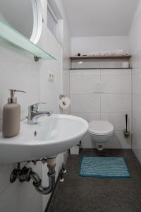 a white bathroom with a sink and a toilet at Studio Luxembourg - EPA in Rust +6 photos
