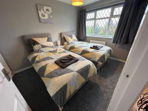 two twin beds in a room with a window at Hinckley Home Leysmill in Hinckley