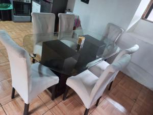 uma mesa de jantar de vidro com cadeiras brancas à volta em SajaHome em Cusco