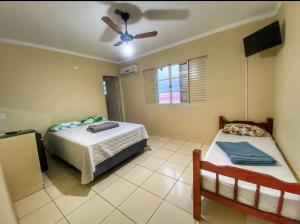 a bedroom with two beds and a ceiling fan at Casarão Hostel in Guaratinguetá
