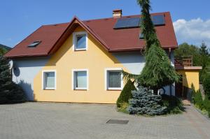 een geel en wit huis met een rood dak bij Davi Penzion & Bowling in Rožňava
