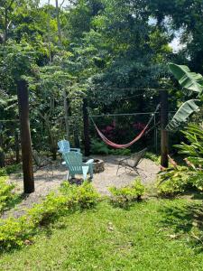 Duas cadeiras e uma rede de descanso num jardim em Casa Serena La Fortuna em La Fortuna