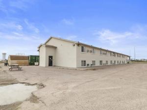 un gran edificio blanco en un estacionamiento en Value Stay Lodge, en Alliance