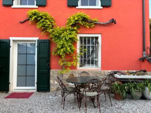 une table et des chaises devant un bâtiment rouge dans l'établissement RedHouse Pesina, à Costermano