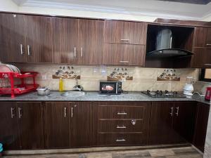 a kitchen with wooden cabinets and a sink and a microwave at Home in Islamabad in Islamabad