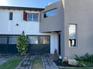 een groot wit huis met een zwarte garage bij Departamento familiar in Coronel Suárez