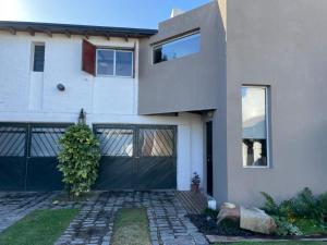 a large white house with a black garage at Departamento familiar in Coronel Suárez