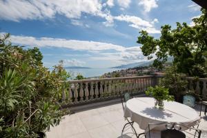 a table on a balcony with a view of the water at Apartments Green Garden in Opatija