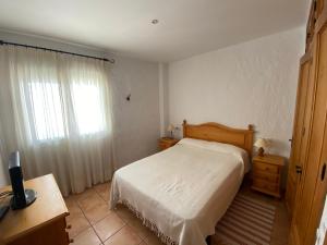 1 dormitorio con cama blanca y ventana en Apartamento CAMPANILLAS, en Conil de la Frontera