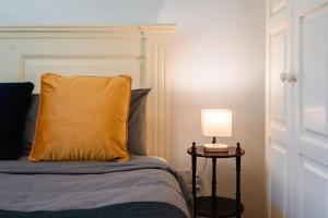 ein Bett mit einem gelben Kissen und einem Tisch mit einer Lampe in der Unterkunft 'Notabile' - Private Townhouse in Mdina in Mdina