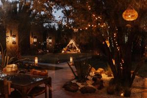 a patio with a fire pit and lights in a yard at L'Ma Lodge in Skoura