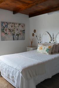 Santa Maria de GuiaにあるLa Casita De Juaniのベッドルーム1室(花が飾られた壁の白い大型ベッド1台付)