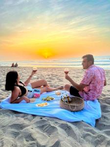 een man en een vrouw op het strand met drankjes bij Cabaña Con Piscina Frente Al Mar in Juan de Acosta