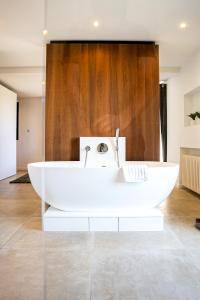 Villa prestige (voiture plage) في كاركيران: حوض استحمام أبيض في غرفة بجدار خشبي