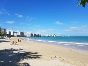 a beach with people sitting on the sand and the ocean at PERLA in Carolina PR 11 Min From Airport in Carolina