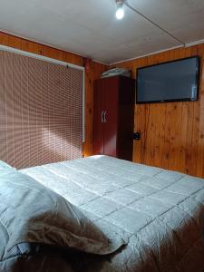 1 dormitorio con 1 cama y TV de pantalla plana en QUELKUN, FAMILIAR en Quellón