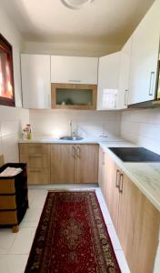 a kitchen with white cabinets and a red rug on the floor at Dhabi Sweet Home in Doglodi