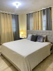un grande letto bianco in una camera da letto con tende di Merengue House a Boca Chica