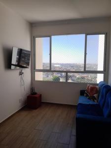 sala de estar con sofá azul y ventana grande en Apartamento do Remanso 2/4, en Hortolândia