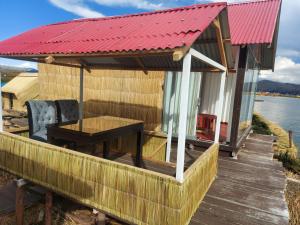 Coila Titicaca lodge في بونو: منزل بسقف احمر وطاولة على سطح السفينة