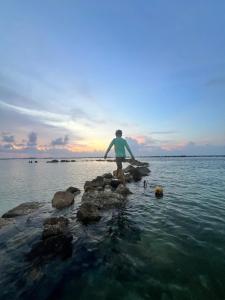 María Chiquita的住宿－Delux Oceanview on the Caribbean @ Playa Escondida Resort，站在水中岩石上的人