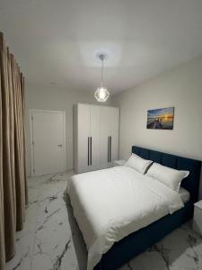 Lushnjë的住宿－Prime Luxury Apartments，一间卧室配有一张大床和蓝色床头板