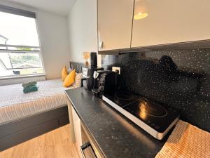 uma pequena cozinha com um fogão e um sofá em Lovely self contained studio now available em Londres