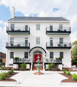 a white house with a red door and a fountain at The Harvey in New Bern