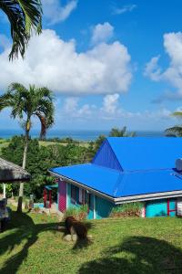 a house with a blue roof and a palm tree at Pipirite Chantant - Maison et Studios vue mer in Sainte-Rose