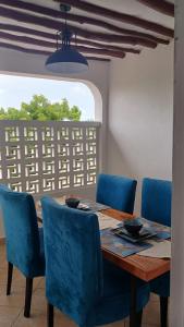 een eettafel met blauwe stoelen en een raam bij Bedroom Diani Beach in Diani Beach