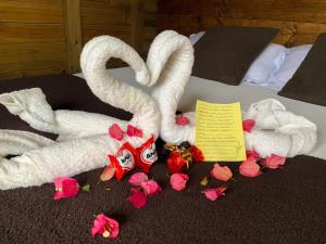 a bed with two swans made out of flowers at Pousada Vale da Magia in Praia do Rosa