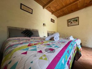 a bedroom with a large bed with a colorful comforter at Casa del viajero colonial in Antigua Guatemala