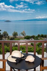 due cappelli appoggiati su un tavolo su un balcone con vista sull'acqua di Lilian Beach Front 3 Skopelos a Panormos Skopelos