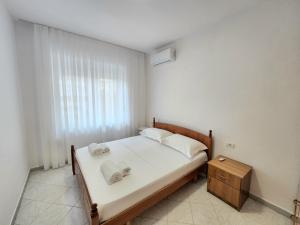 um quarto com uma cama com lençóis brancos e toalhas em Rustic City Center Vibes em Tirana