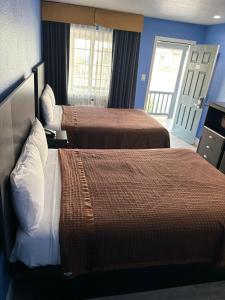 モントレーにあるThe Monterey Fireplace Innのベッド2台とドアが備わるホテルルームです。