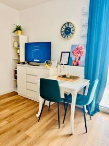 una scrivania bianca con 2 sedie e un tavolo con una TV di Apartament Lazurowa a Varsavia
