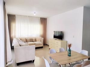 uma sala de estar com um sofá, uma mesa e cadeiras em Confortable Apartamento con Piscina en Cabrera em Cabrera