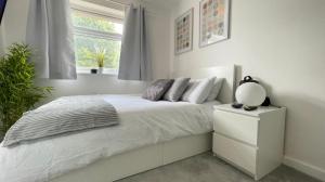 a white bedroom with a bed and a window at Lovely 3 bedroom house near city centre - Basildon in Basildon