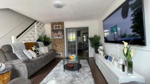 ein Wohnzimmer mit einem Sofa und einem TV in der Unterkunft Lovely 3bedroom house near city centre - Basildon in Basildon
