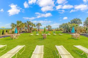 a lawn with chairs and tables and umbrellas at Ocean View Double Suite! Sleeps 4 Meridian Plaza 705 in Myrtle Beach