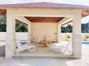 um pavilhão com cadeiras, uma mesa e uma piscina em Confortable Apartamento con Piscina en Cabrera em Cabrera