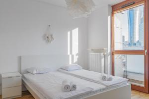 a white bedroom with a bed and a window at Chłodna 48 by NYX Apart in Warsaw