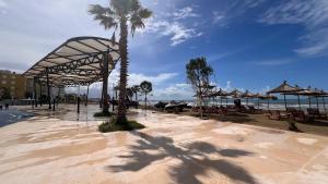 een strand met een palmboom en tafels en parasols bij Mikael Apartment in Durrës